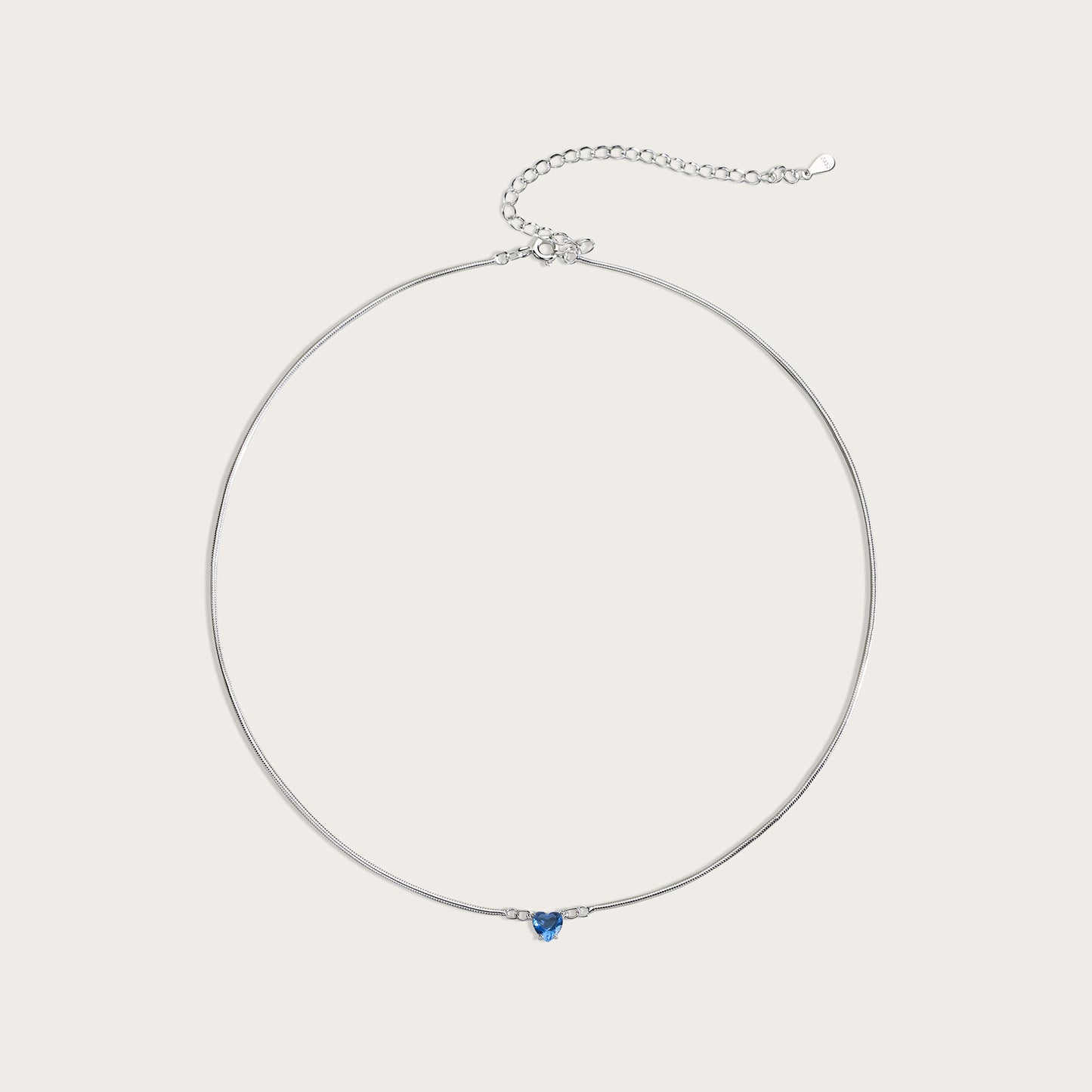 Silver necklace with a blue gemstone on a light gray background