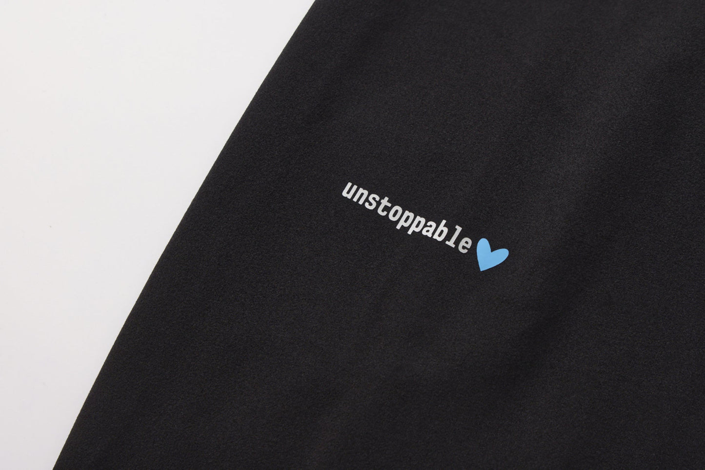 Black fabric with 'unstoppable' text and blue heart symbol on a white background