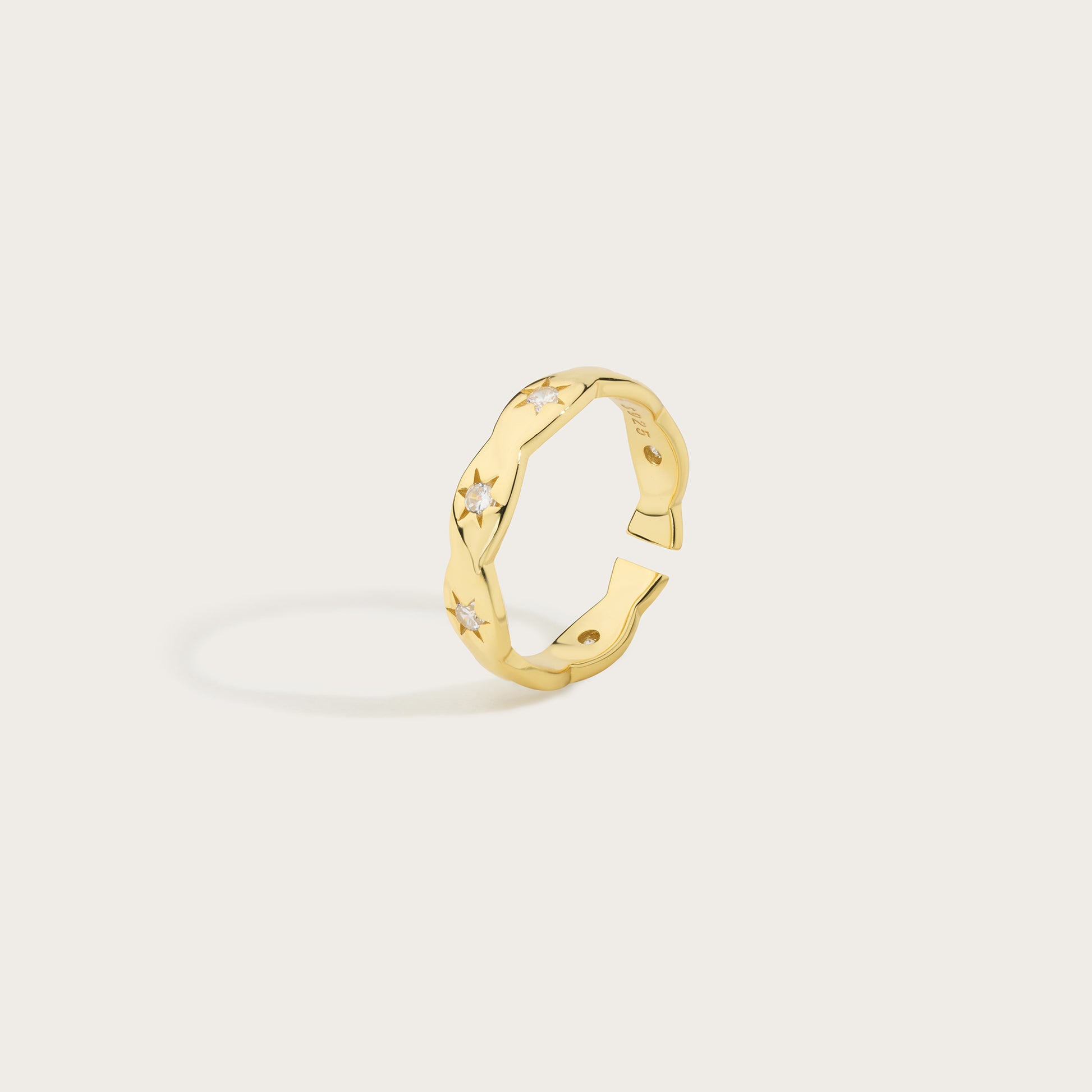 Gold ring with geometric design on a light beige background