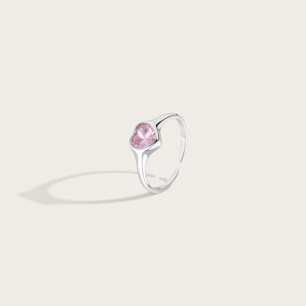 Silver ring with a pink heart gemstone on a light gray background