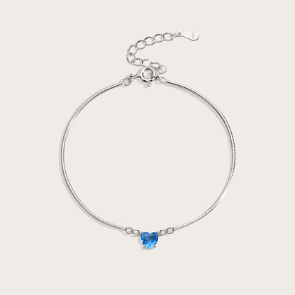 Silver bracelet with a heart-shaped blue gemstone on a light gray background
