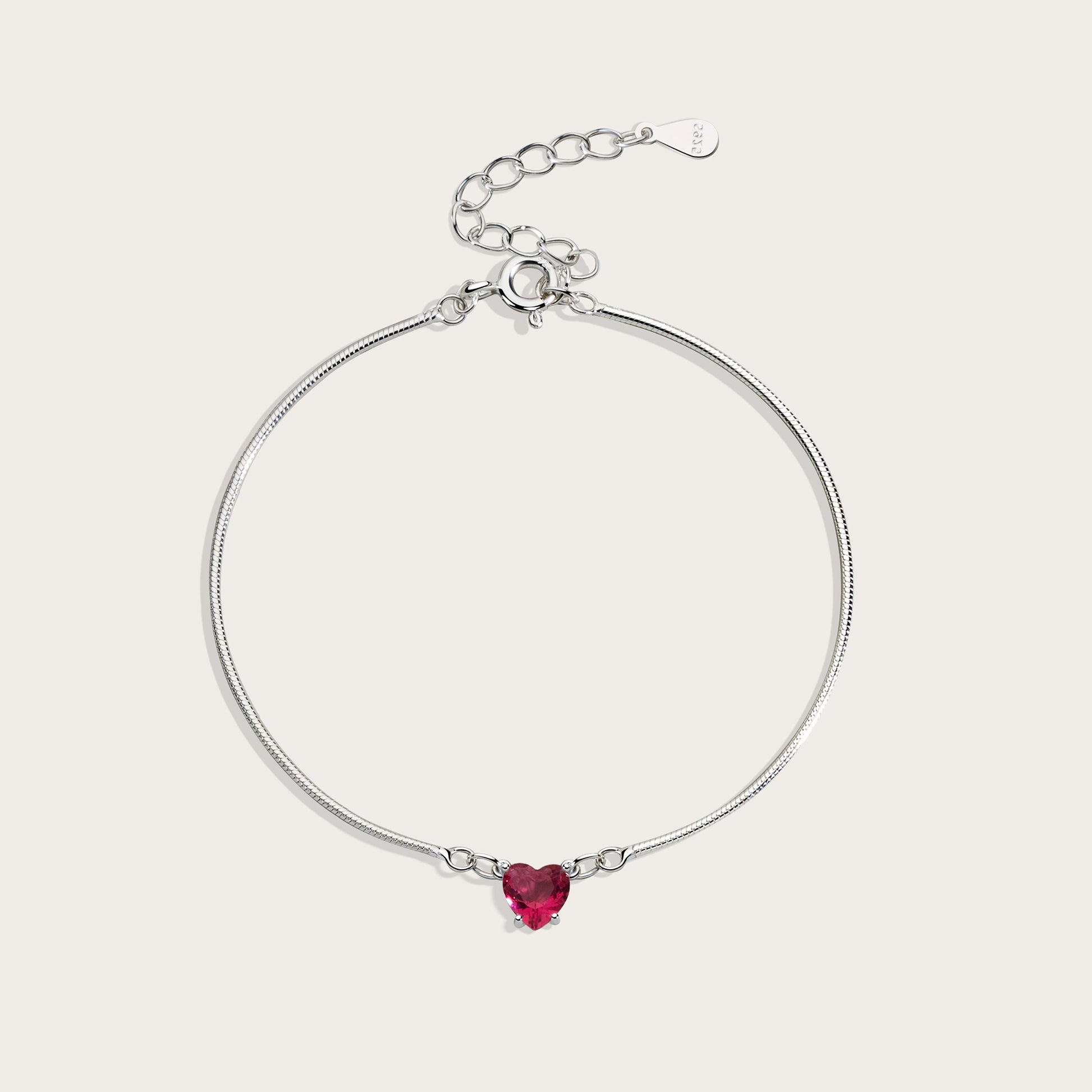 Silver bracelet with a heart-shaped red gemstone on a light gray background