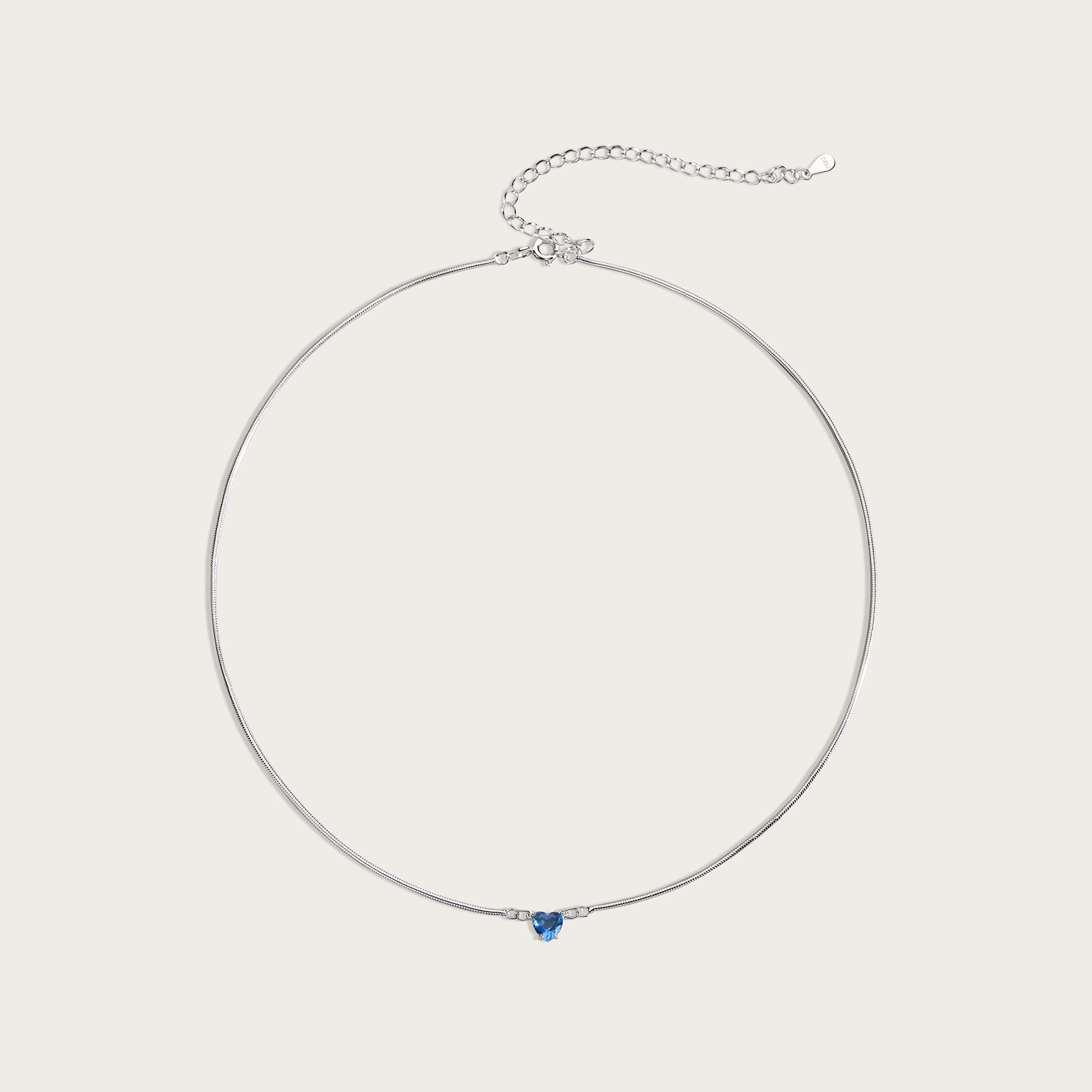 Silver necklace with a blue gemstone on a light gray background